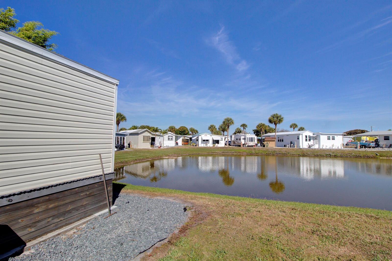 A view of a pond surrounded by mobile homes under a clear blue sky — 6633 SE 52nd Street, Okeechobee FL 34974, OKEECHOBEE, FL