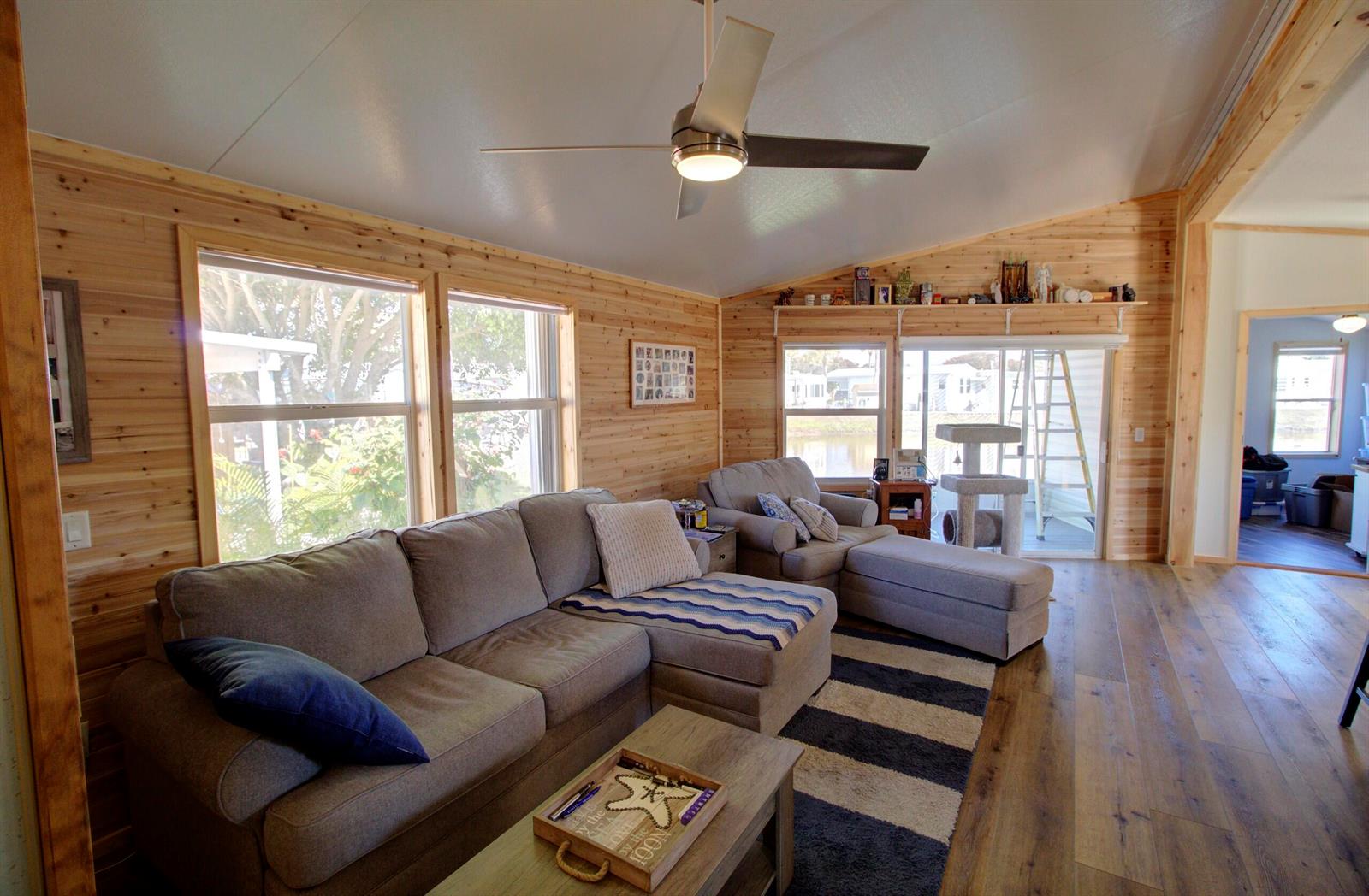A living room features wood-paneled walls, a sectional sofa, and a ceiling fan — 6633 SE 52nd Street, Okeechobee FL 34974, OKEECHOBEE, FL