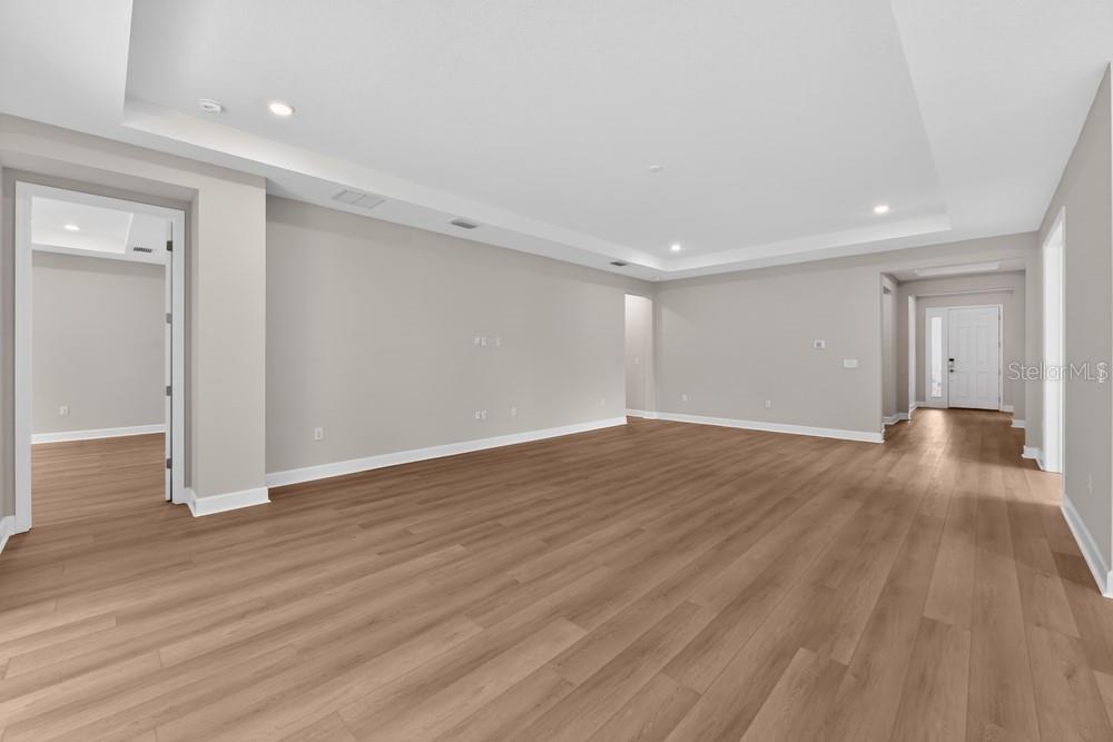 An empty room with light wood-look flooring, gray walls, and a tray ceiling — 6913 PRAIRIE OAK WAY, NOKOMIS, FL