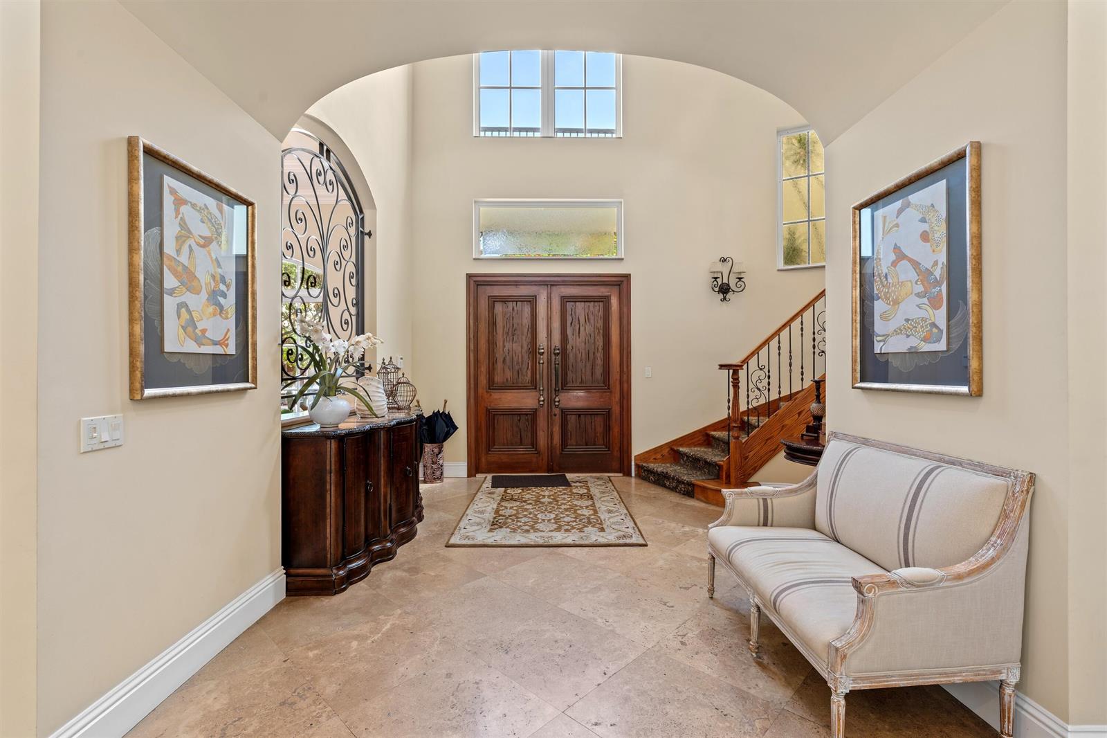A grand foyer features a high arched ceiling, stone tile floors, and a wooden staircase — 1232 Seaspray Avenue, Delray Beach FL 33483, DELRAY BEACH, FL