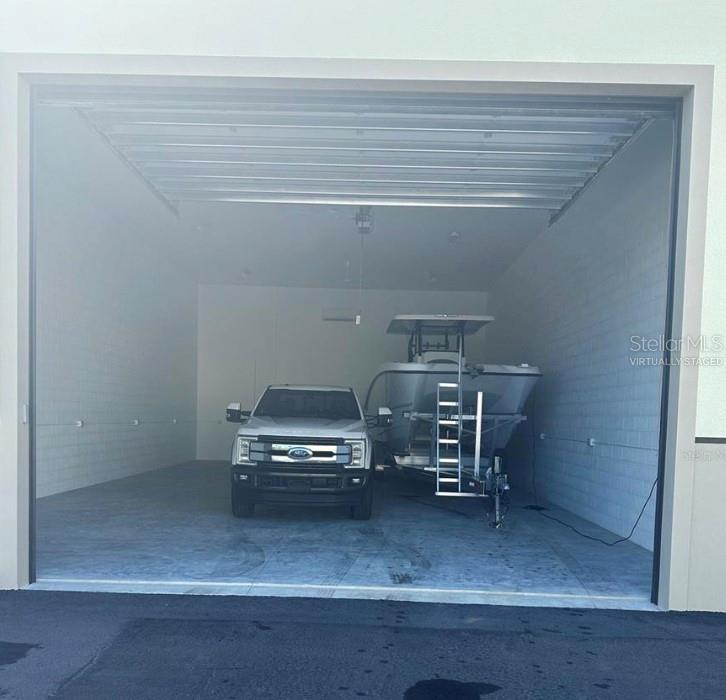 This is a virtually staged image of a large garage containing a truck and boat — 25155 AIRPORT ROAD UNIT E-7, PUNTA GORDA, FL
