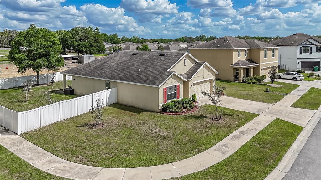 An aerial view shows a single-story tan house with a white fence and driveway — 35900 HILLBROOK AVENUE, ZEPHYRHILLS, FL