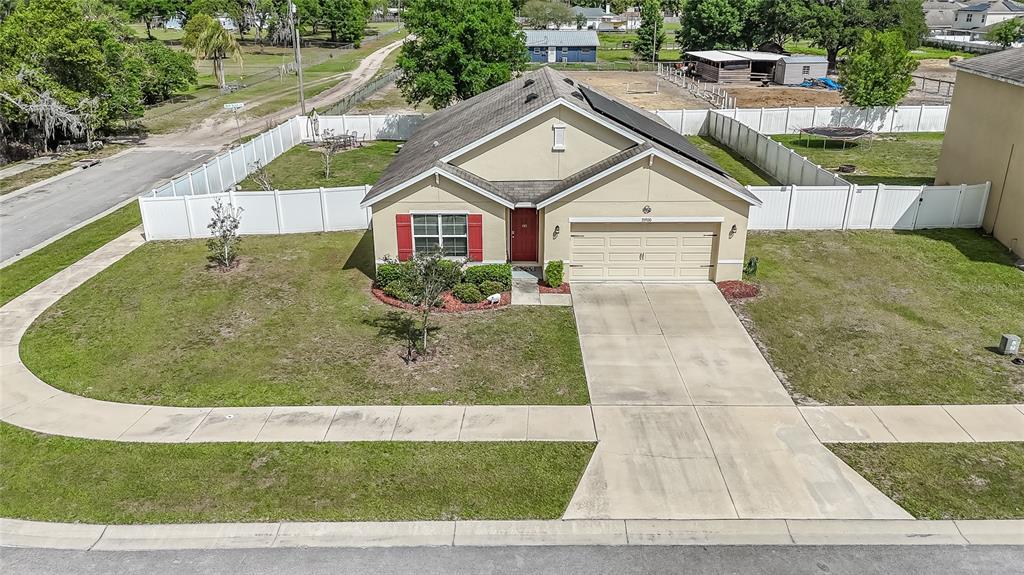 An aerial view of a single-story suburban house with a tan exterior and red shutters — 35900 HILLBROOK AVENUE, ZEPHYRHILLS, FL