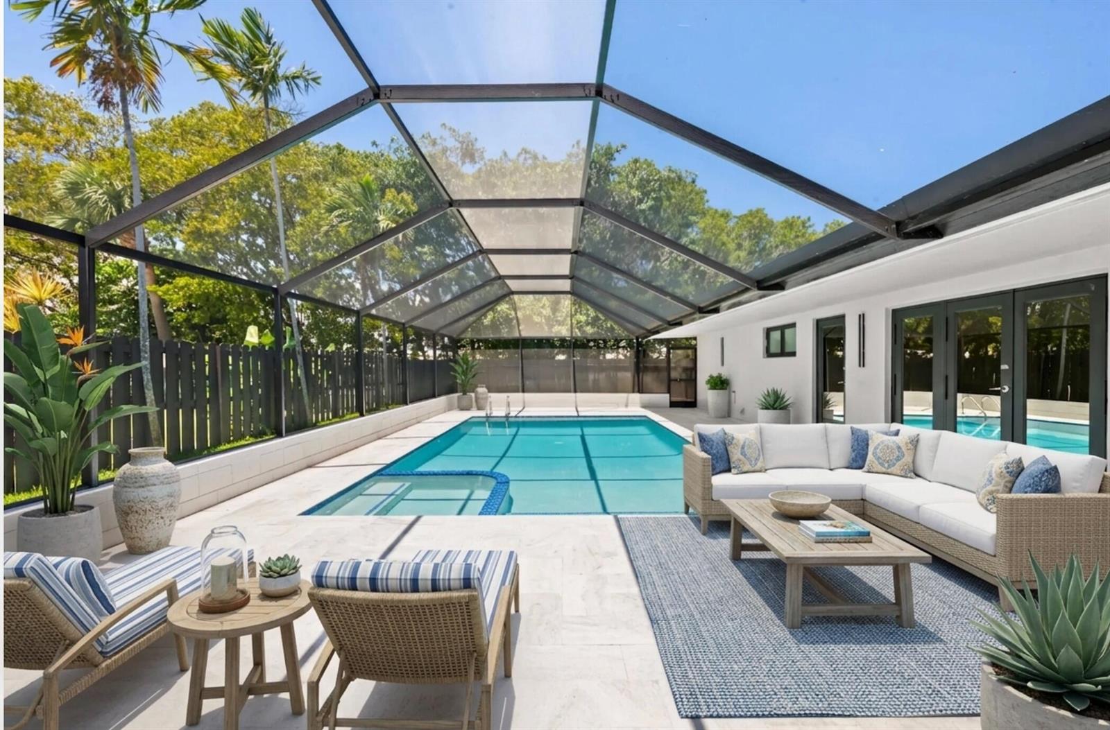 A screened-in pool patio features a lounge area with white furniture and light stone flooring — 2811 NE 53rd Court, Lighthouse Point FL 33064, LIGHTHOUSE POINT, FL