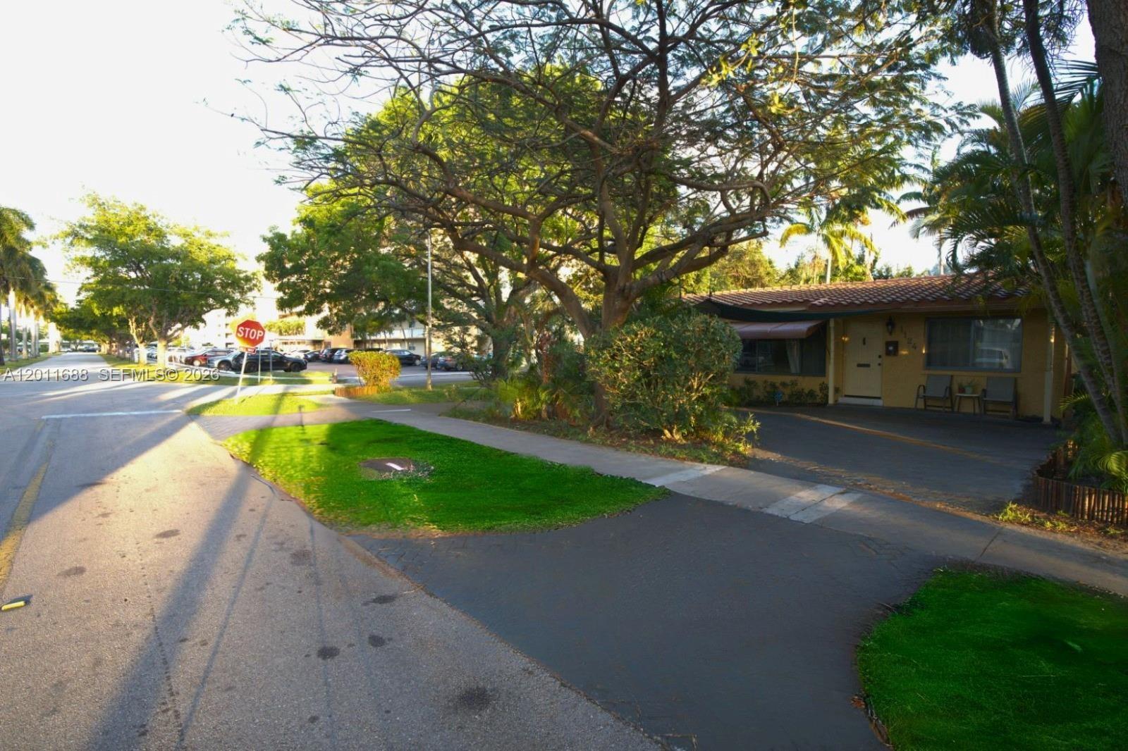 A single-story house with a paved driveway and a large tree in the front yard — 1124 NE 7th St, Hallandale Beach FL 33009, HALLANDALE BEACH, FL