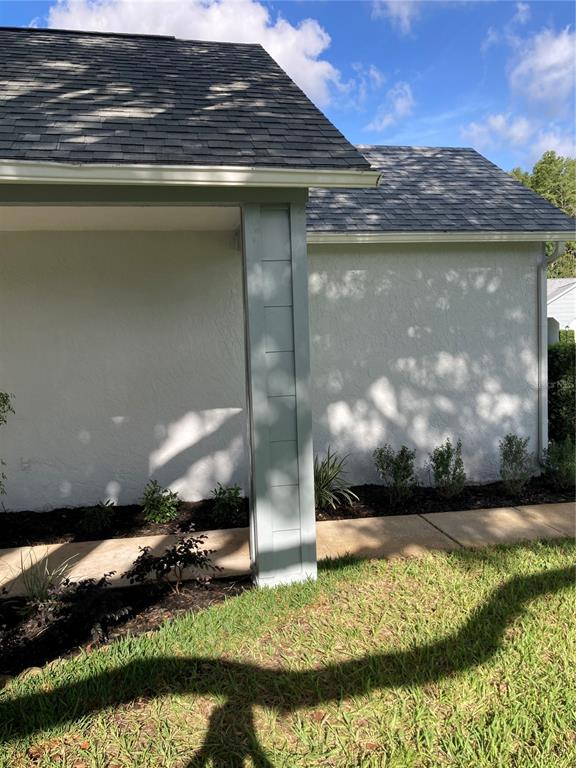 A view of a house exterior featuring a white stucco wall, gray roof, and porch column — 9545 DANVILLE COURT UNIT 42, NEW PORT RICHEY, FL