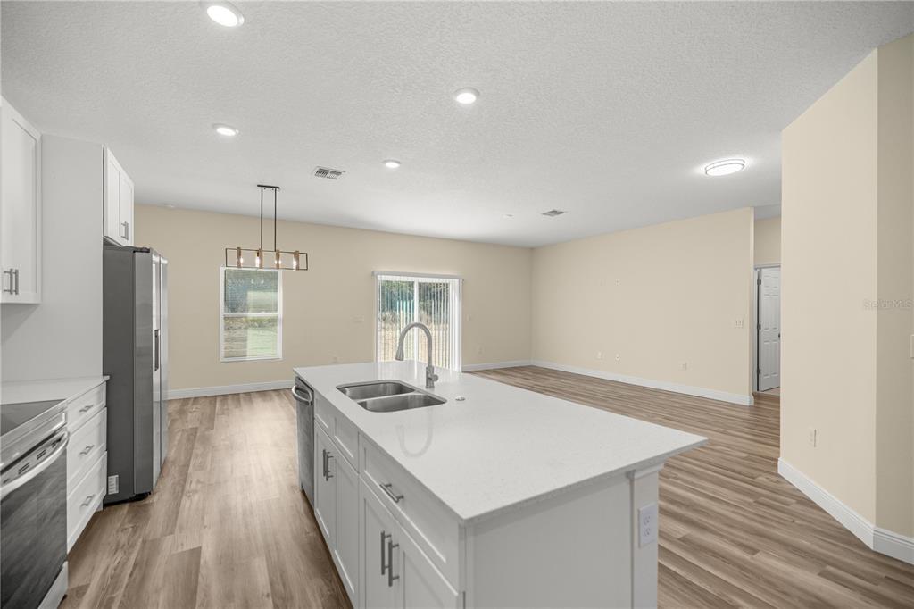 A kitchen with white cabinets, stainless steel appliances, a center island, and wood-look flooring — 13745 SW 43RD CIRCLE, OCALA, FL