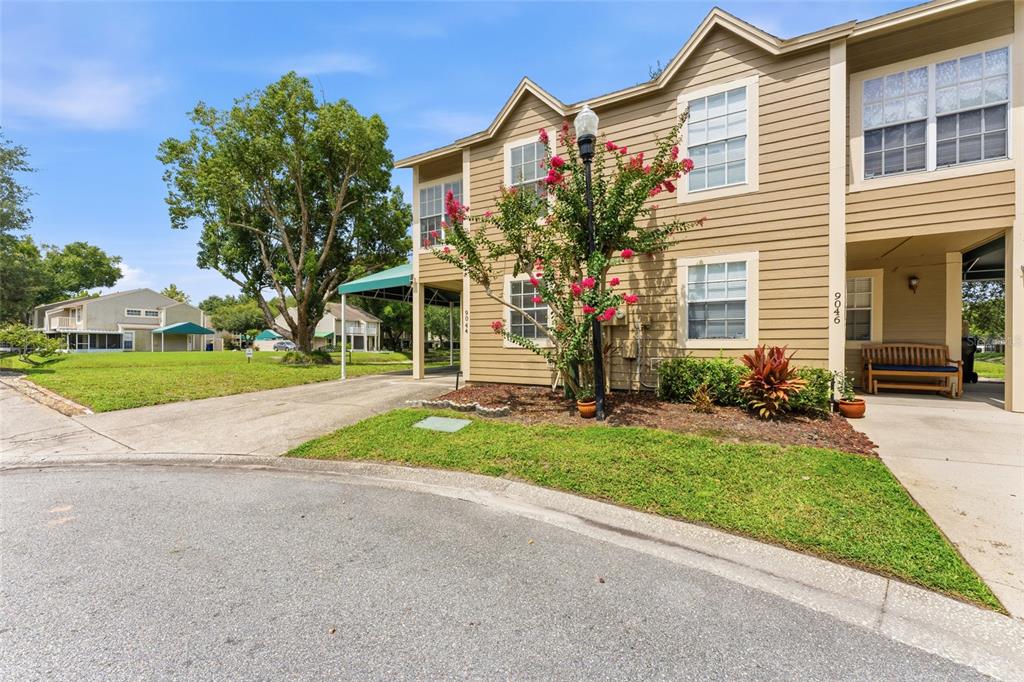 A two-story tan building with a covered entryway and a small front garden — 9044 LAKE PLACE LANE, TAMPA, FL
