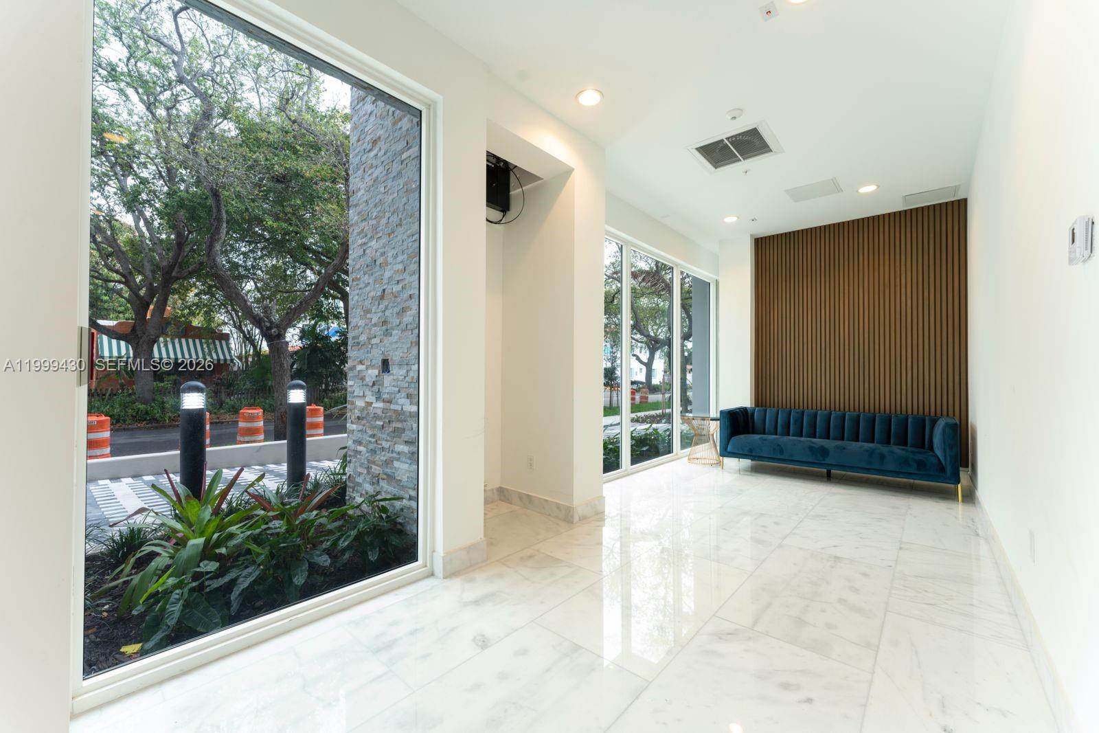 A modern lobby features marble floors, a blue velvet sofa, and floor-to-ceiling windows — 1850 Monroe St # 306, Hollywood FL 33020, HOLLYWOOD, FL