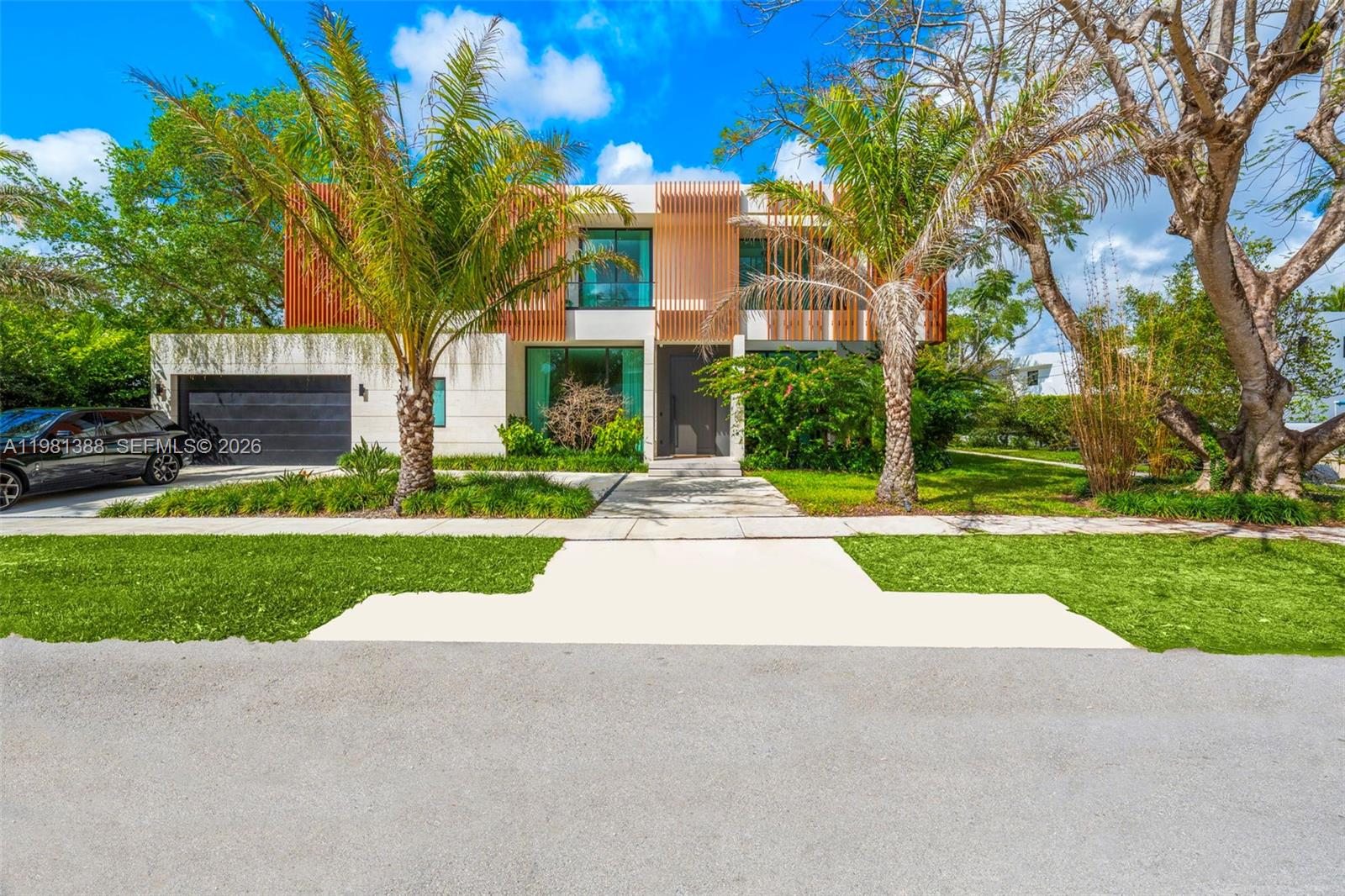 An aerial view of a modern two-story house featuring vertical wood slat accents and landscaping — 7700 SW 50th Ct, Miami FL 33143, MIAMI, FL