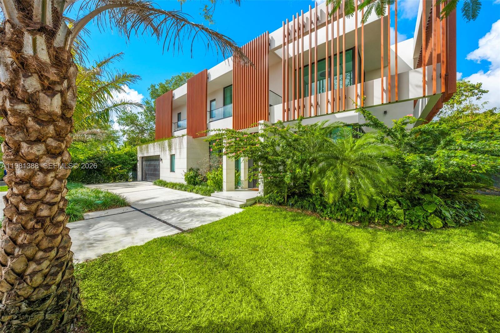 A modern entryway features a floating wooden staircase, a pebble garden, and a large door — 7700 SW 50th Ct, Miami FL 33143, MIAMI, FL