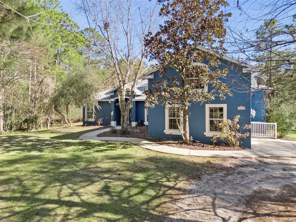 An aerial view of a blue house with a swimming pool surrounded by dense forest — 3441 HICKORY CREEK ROAD, DELTONA, FL