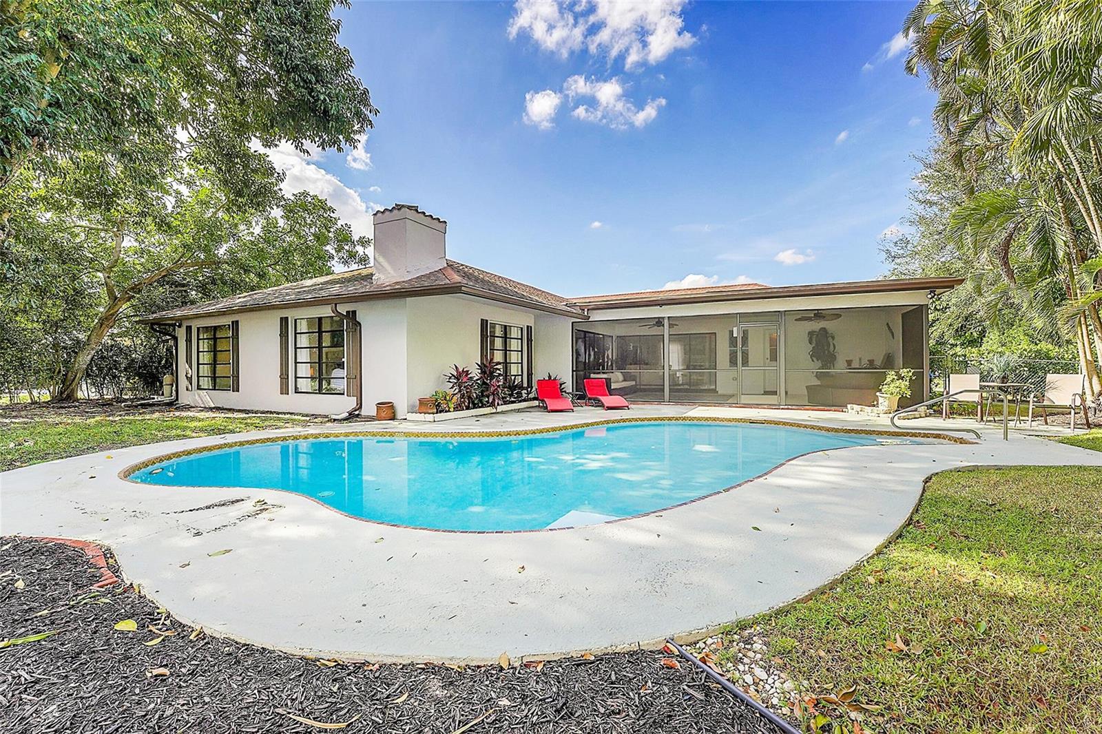 A white house with a swimming pool, screened-in patio, and red lounge chairs — 1618 The 12th Fairway, Wellington FL 33414, WELLINGTON, FL