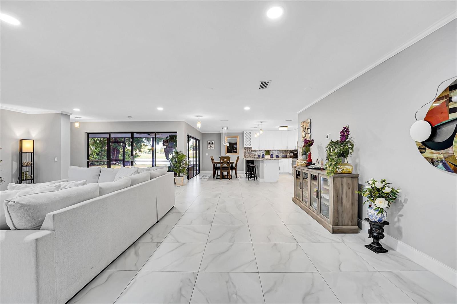 An open-concept living and dining area features white marble-look tile floors and a modern kitchen — 1618 The 12th Fairway, Wellington FL 33414, WELLINGTON, FL