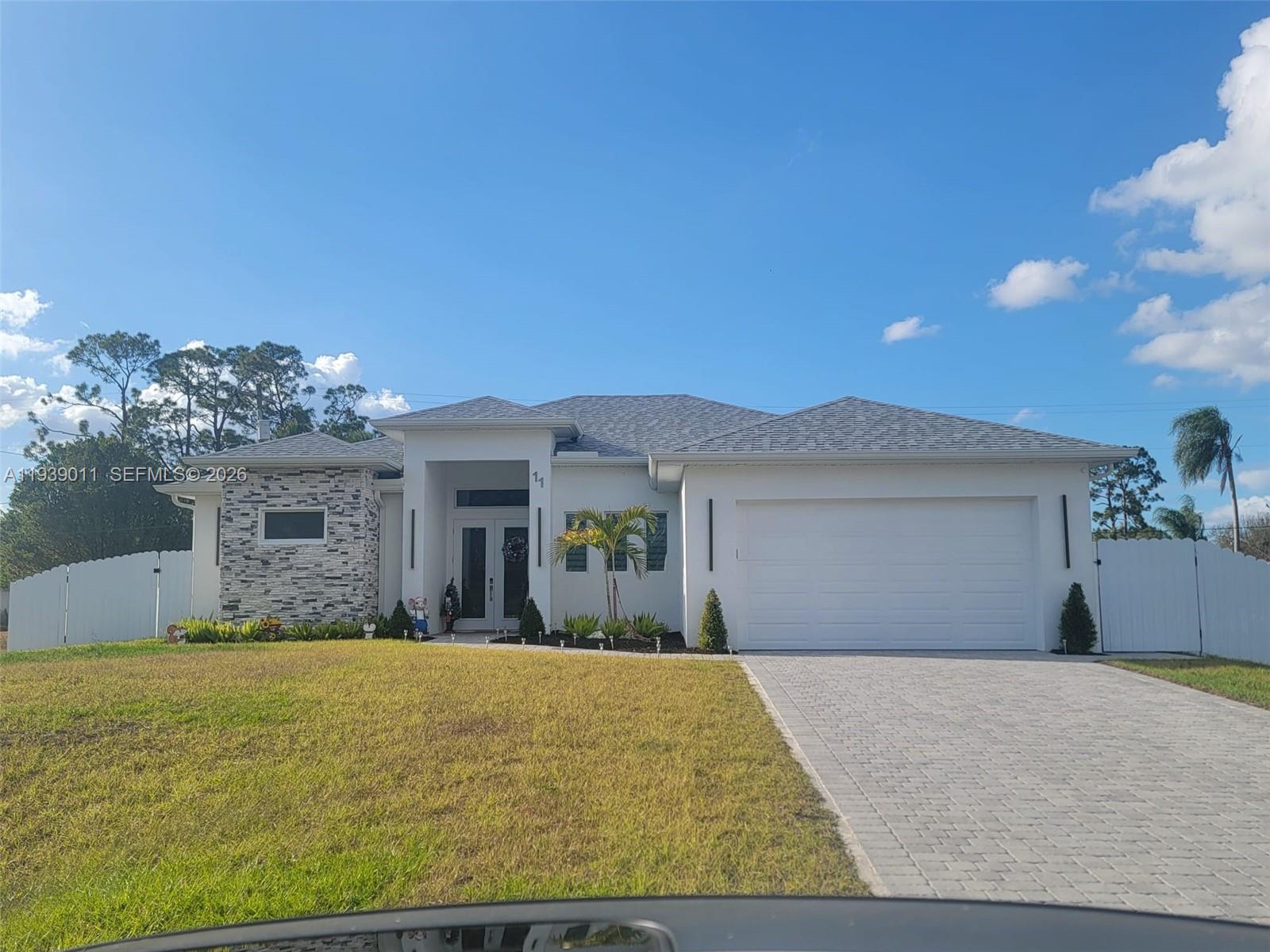 A single-story house with a stone-accented facade, white walls, and a paved driveway — 11 Connecticut Rd, Lehigh Acres FL 33936, LEHIGH ACRES, FL