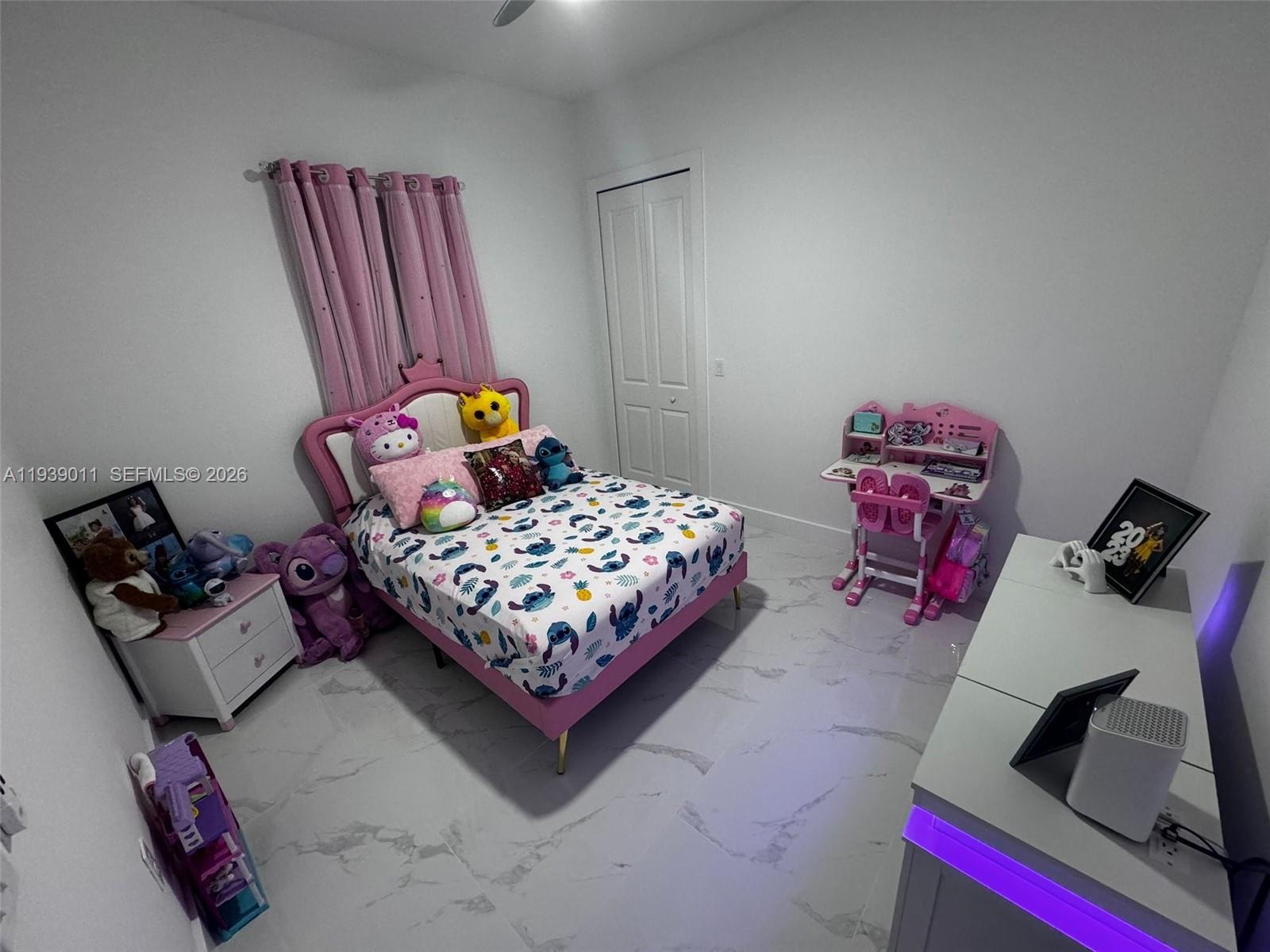 A bedroom features a pink bed, a small desk, and white tile flooring — 11 Connecticut Rd, Lehigh Acres FL 33936, LEHIGH ACRES, FL