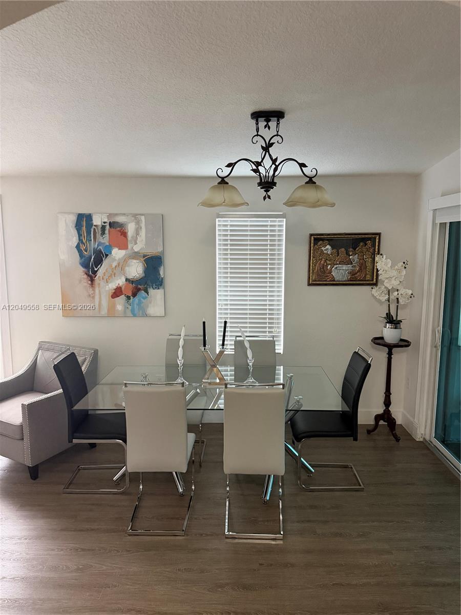 A dining room features a glass-topped table, modern chairs, a chandelier, and wall art — 2642 Atlantic Ave, Opa-Locka FL 33054, OPA-LOCKA, FL