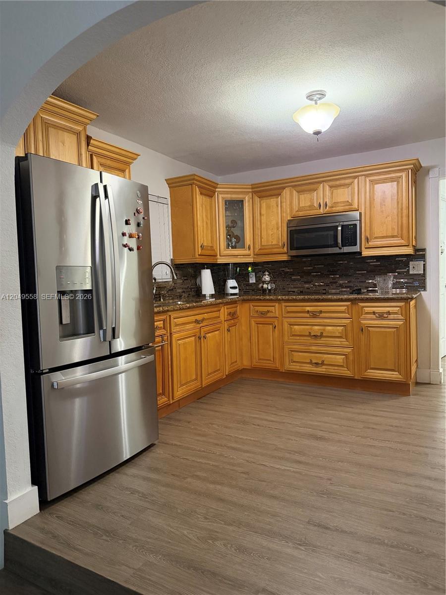 A kitchen features wood cabinets, stainless steel appliances, and a dark tile backsplash — 2642 Atlantic Ave, Opa-Locka FL 33054, OPA-LOCKA, FL