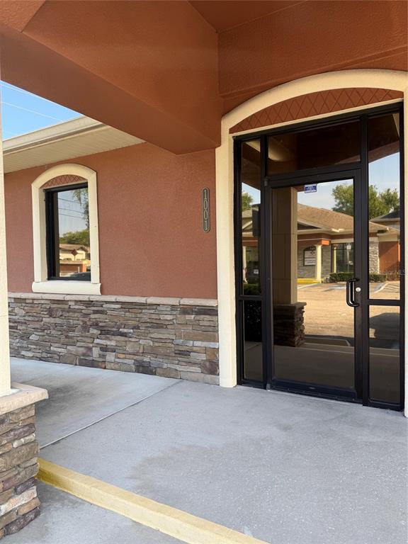 The exterior entrance features a glass door, stone siding, and a window under an overhang — 711 CIARA CREEK COVE UNIT 1001, LONGWOOD, FL