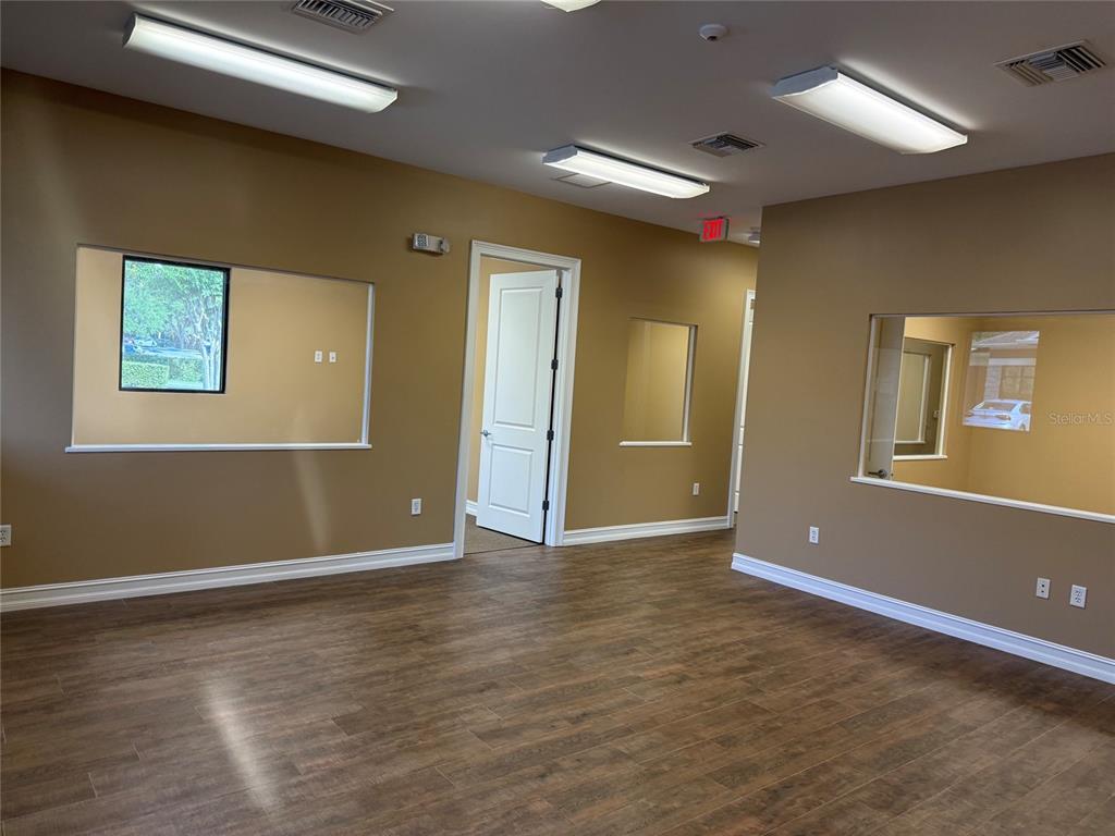 An office space with tan walls, wood-look flooring, multiple interior windows, and recessed lighting — 711 CIARA CREEK COVE UNIT 1001, LONGWOOD, FL