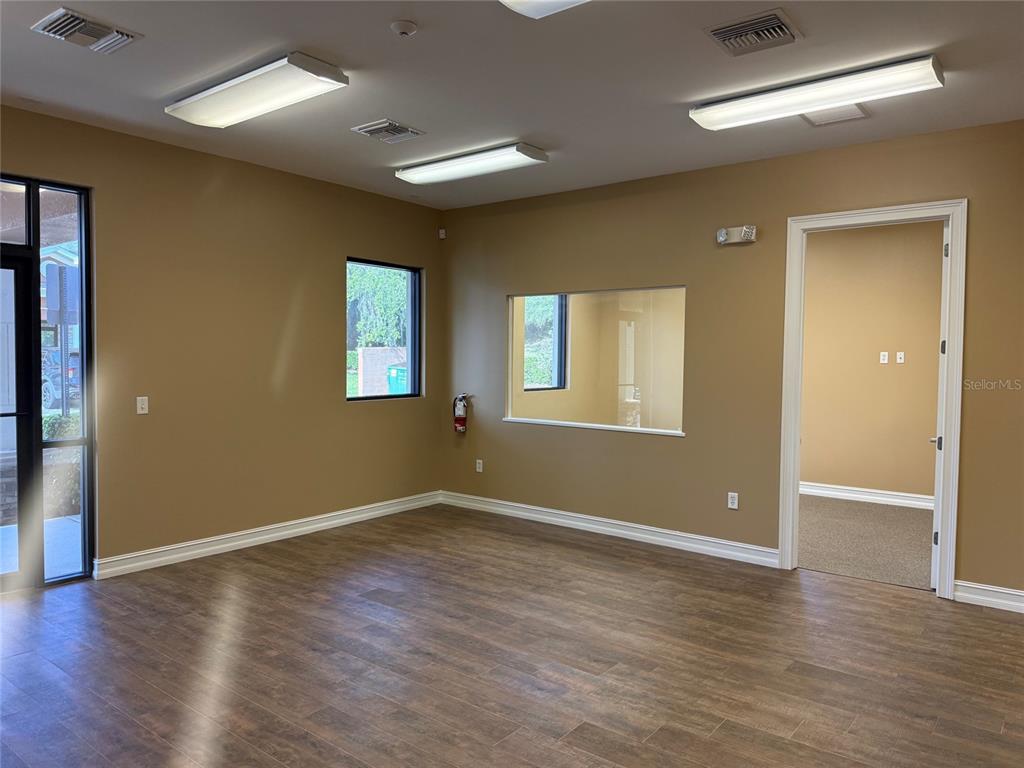 An office room features wood-look flooring, tan walls, recessed lighting, and a windowed interior partition — 711 CIARA CREEK COVE UNIT 1001, LONGWOOD, FL