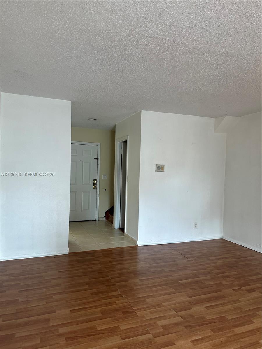 This interior view shows a living area with wood-look flooring and a white entry door — 18101 NW 68th Ave # B201, Hialeah FL 33015, HIALEAH, FL