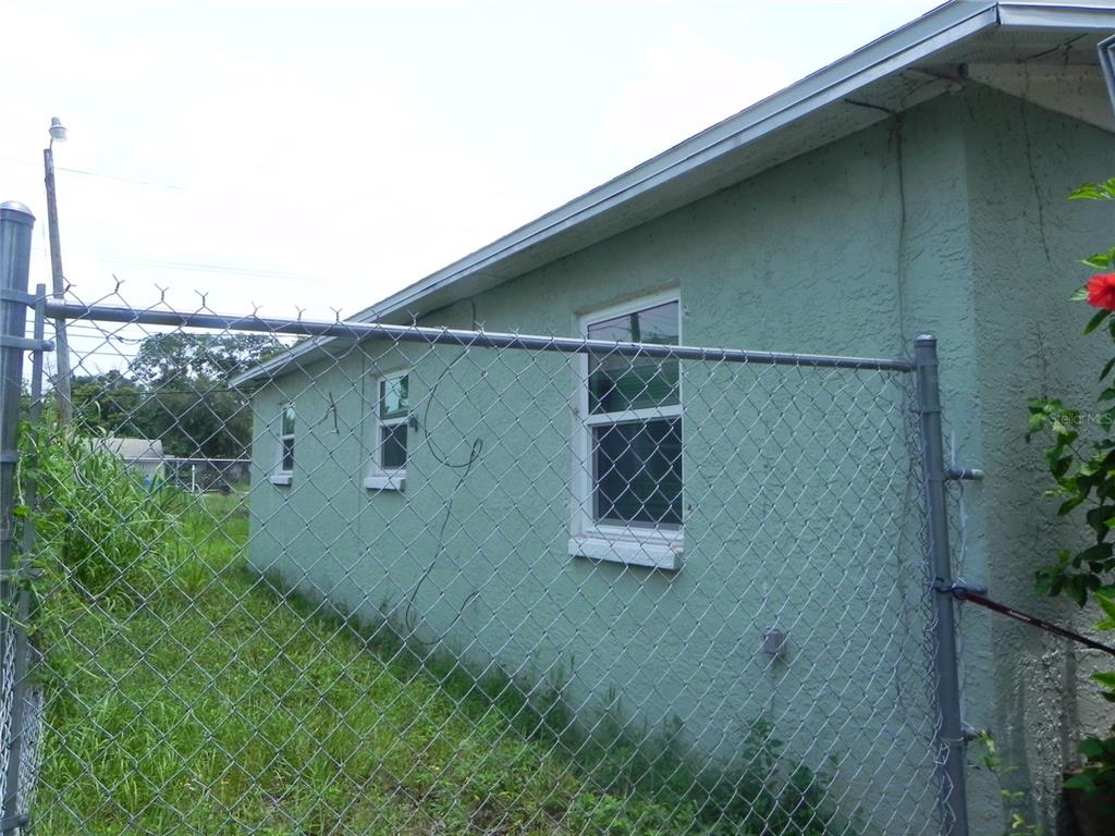 A side view of a light green stucco house exterior with a chain-link fence — 2021 16TH AVENUE S, ST PETERSBURG, FL