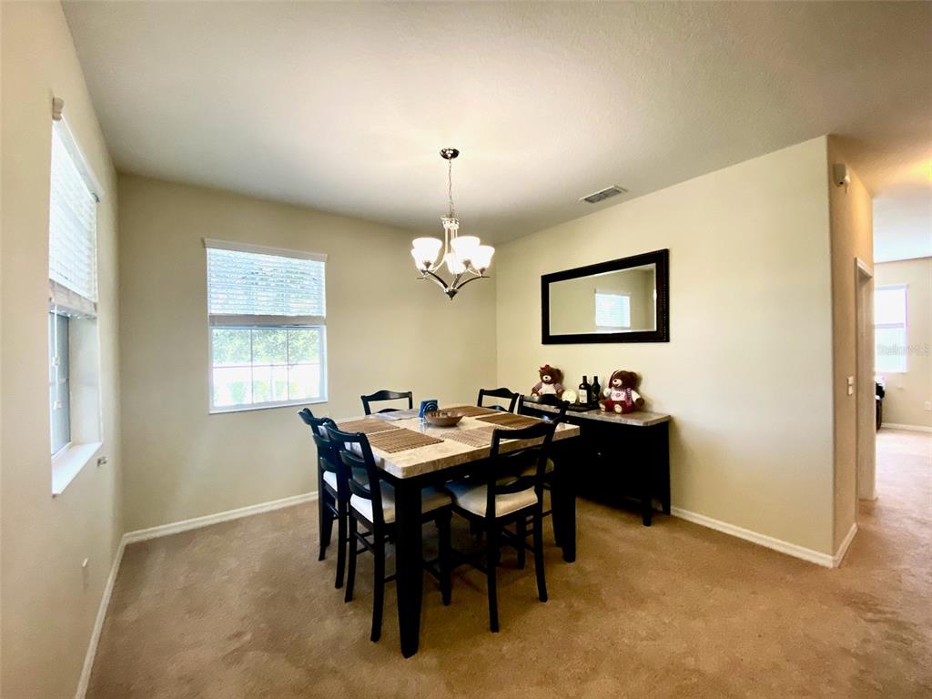 A dining room features a square table with four chairs, a chandelier, and a sideboard — 12802 STRODE LANE, WINDERMERE, FL
