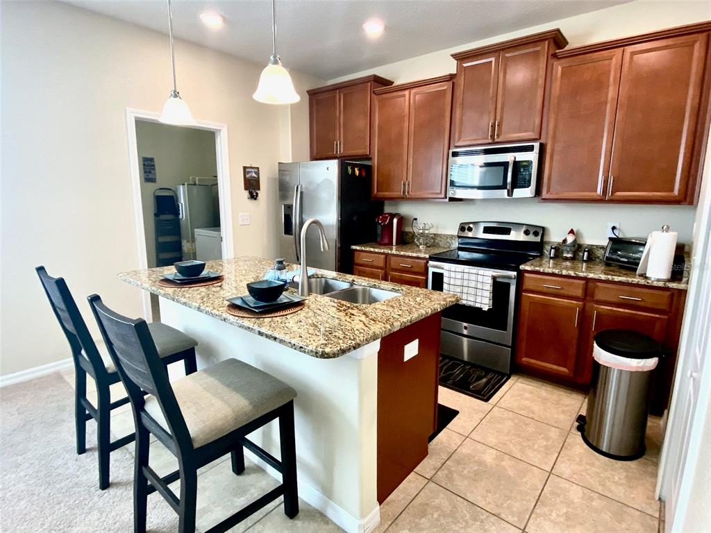 A kitchen features wood cabinets, granite countertops, stainless steel appliances, and a breakfast bar island — 12802 STRODE LANE, WINDERMERE, FL