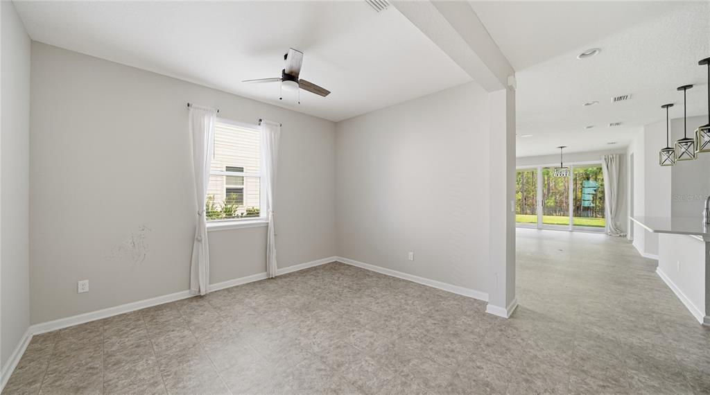 An empty dining area with tile flooring, a ceiling fan, and a view into the living room — 1937 AMBERLY DRIVE, MIDDLEBURG, FL