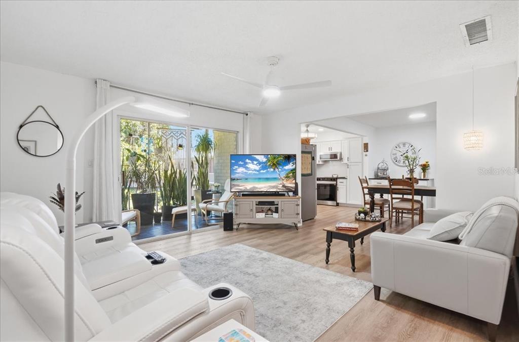 A living room with white leather sofas, a television, and a sliding door to a patio — 4138 37TH STREET S UNIT 144, ST PETERSBURG, FL