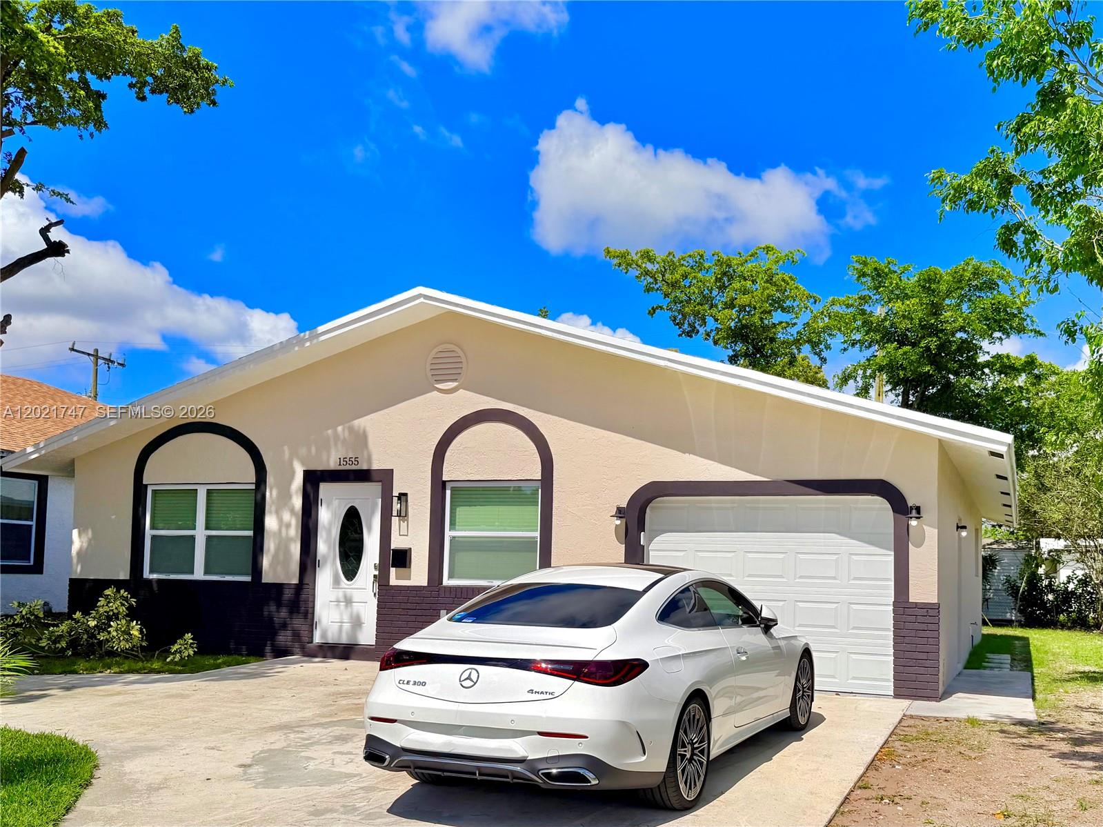 A single-story house features a tan stucco exterior with dark brick accents and a garage — 1555 NW 6th Ave, Pompano Beach FL 33060, POMPANO BEACH, FL