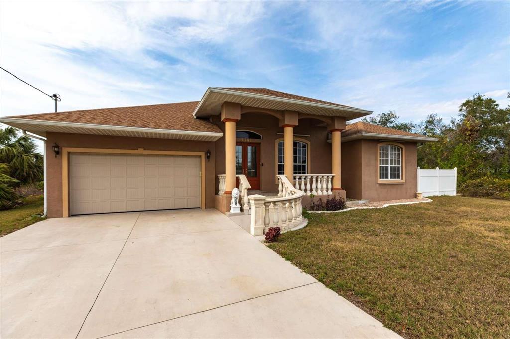A single-story house with a brown stucco exterior, a two-car garage, and a front porch — 3391 KNOX TERRACE, PORT CHARLOTTE, FL
