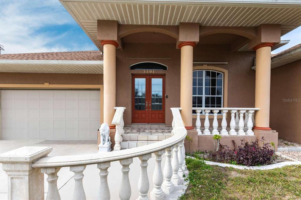 The exterior of a house features a covered porch with columns, balustrades, and double doors — 3391 KNOX TERRACE, PORT CHARLOTTE, FL