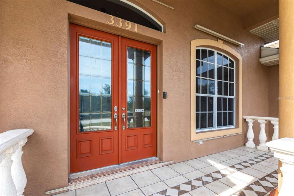 A front porch features a double red door with glass panels and a tiled floor — 3391 KNOX TERRACE, PORT CHARLOTTE, FL
