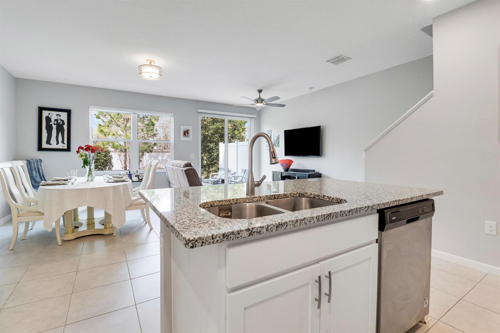A kitchen island with a granite countertop and stainless steel sink overlooks a dining area — 303 SE Halifax Lane, Stuart FL 34994, STUART, FL