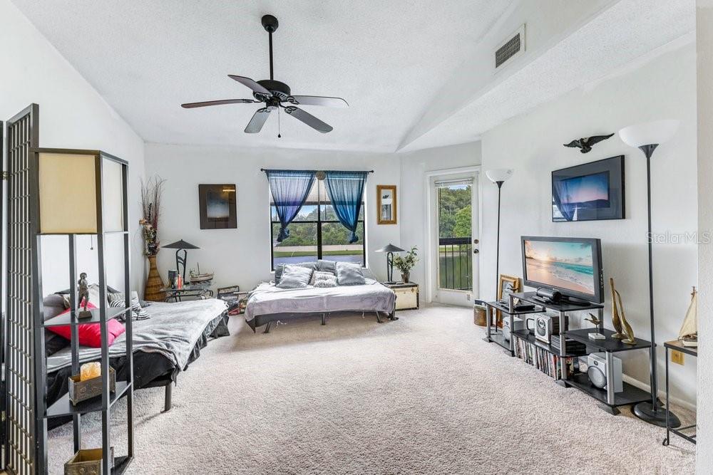A carpeted living room features a vaulted ceiling, a ceiling fan, and a sliding glass door — 2231 CASCADES BOULEVARD UNIT 304, KISSIMMEE, FL