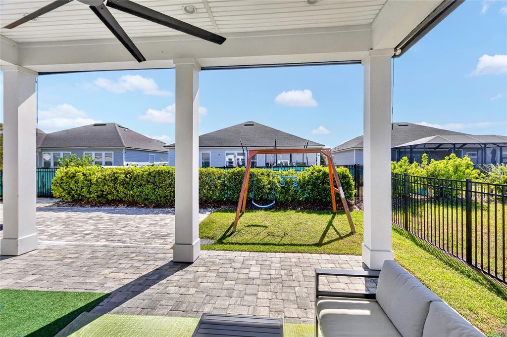 A covered patio features a paved floor, a swing set, and a view of neighboring houses — 3289 SW 120TH TERRACE, GAINESVILLE, FL