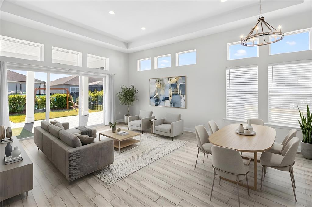 This open-concept living and dining area features light wood-look tile floors and large windows — 3289 SW 120TH TERRACE, GAINESVILLE, FL