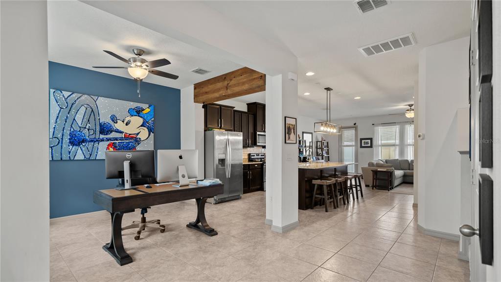 An open-concept home features a home office with a Mickey Mouse painting and a kitchen — 8113 RED STOPPER LANE, WINTER GARDEN, FL