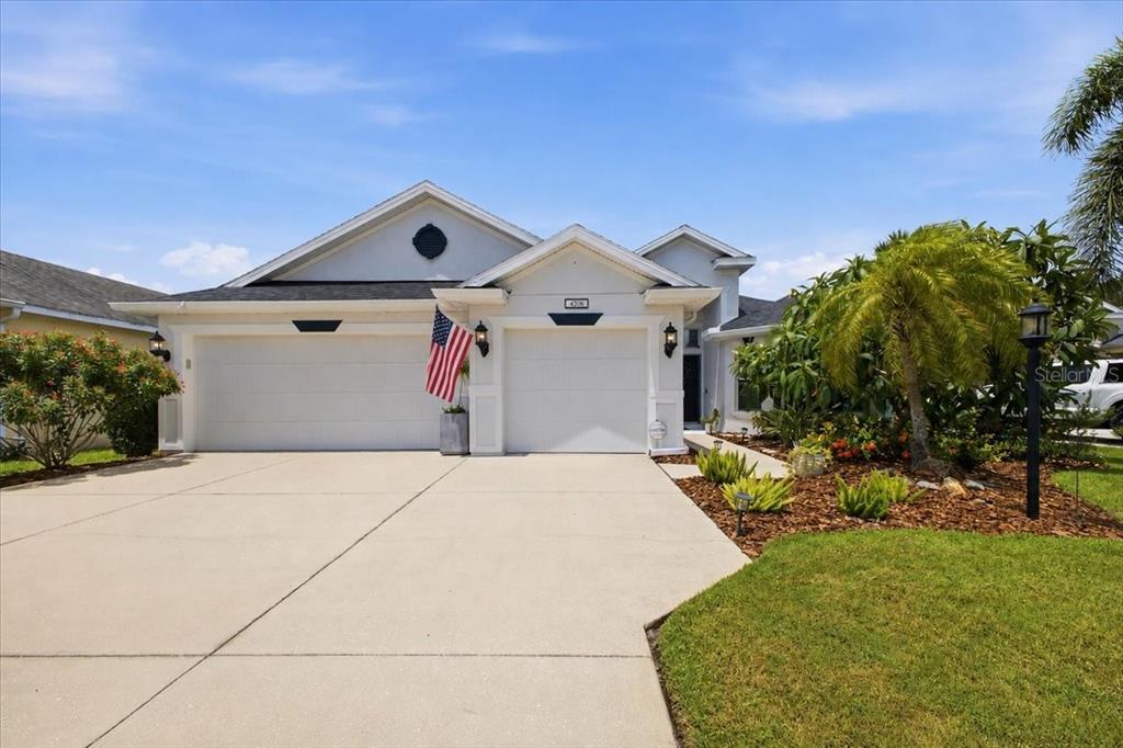 A single-story suburban house with a two-car garage, white stucco exterior, and landscaped front yard — 4708 TILDEN PARK COURT, BRADENTON, FL