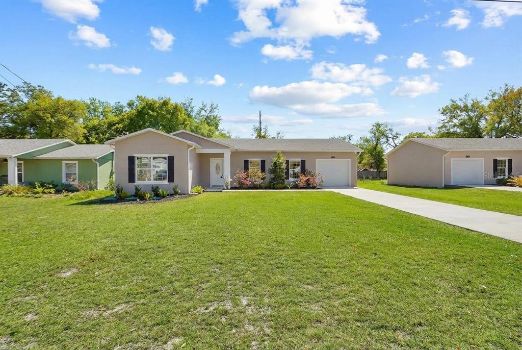A single-story house with a beige exterior, a white garage door, and a grassy front yard — 178 DOVER LANE, DELAND, FL