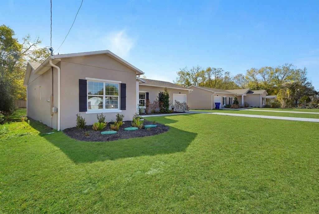 A beige single-story house with dark shutters and a landscaped front yard under a blue sky — 178 DOVER LANE, DELAND, FL