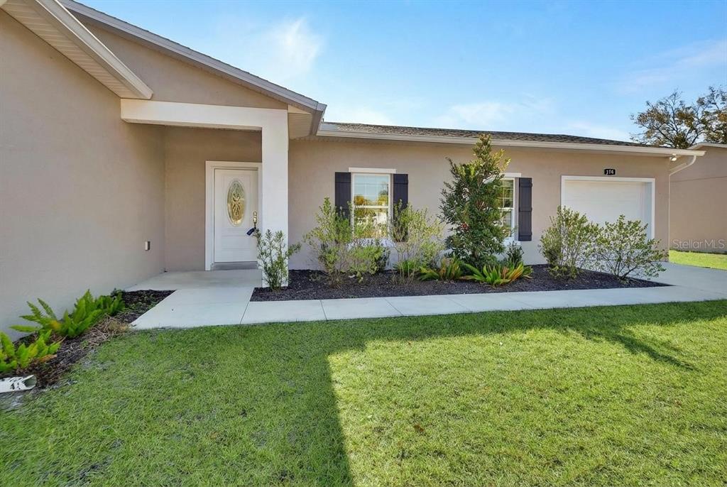 A single-story house exterior with a white front door, garage, and landscaped front yard — 178 DOVER LANE, DELAND, FL