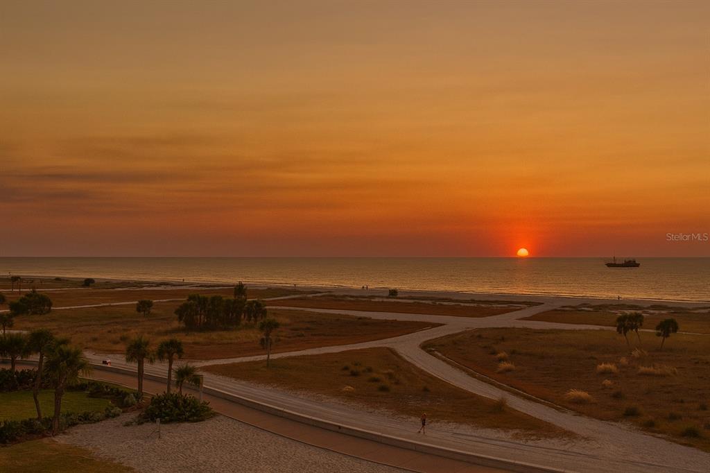A high-angle view of a beach at sunset with a ship on the horizon — 11500 GULF BOULEVARD UNIT 504, TREASURE ISLAND, FL