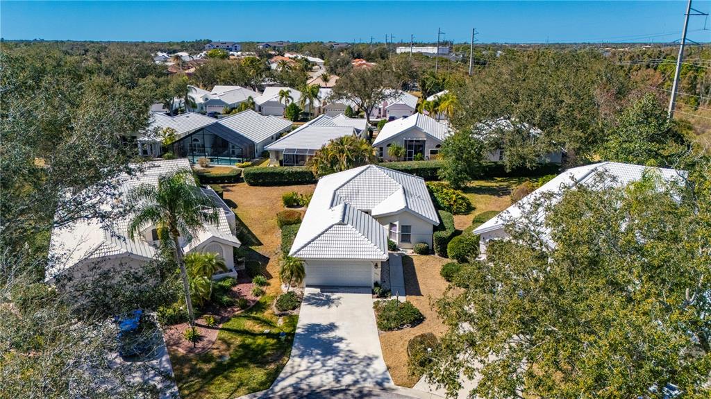 An aerial view shows a suburban neighborhood with several single-story houses featuring white roofs — 1029 HARBOR TOWN DRIVE, VENICE, FL