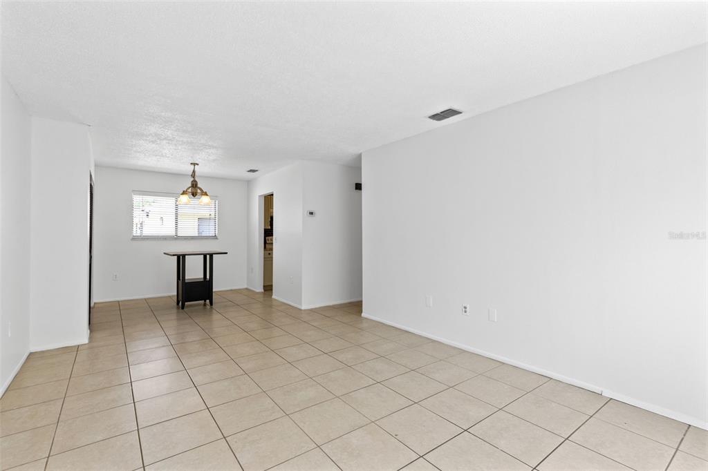 An empty room with white walls, tile flooring, and a dining area with a light fixture — 343 SAN MIGUEL STREET UNIT 343, WINTER SPRINGS, FL