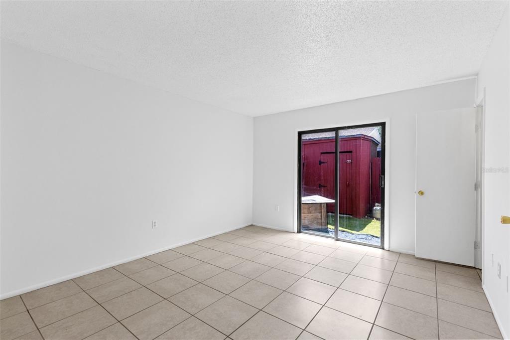 An empty room with light-colored tile flooring, white walls, and a sliding glass door — 343 SAN MIGUEL STREET UNIT 343, WINTER SPRINGS, FL