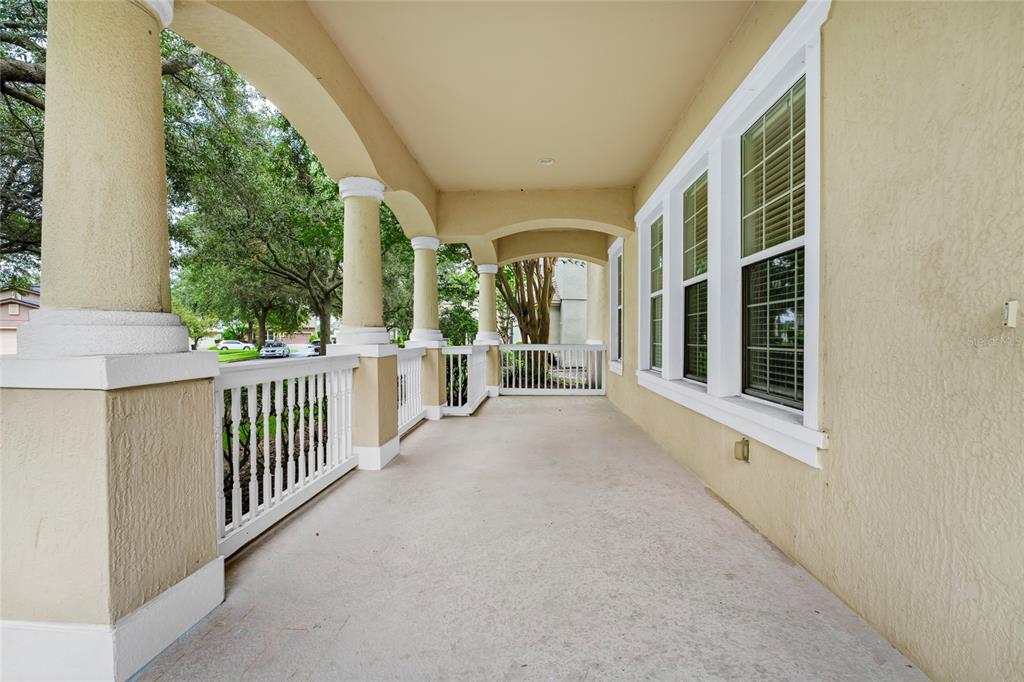 A covered porch with beige stucco walls, white railings, and several columns — 12718 BIDEFORD AVENUE, WINDERMERE, FL