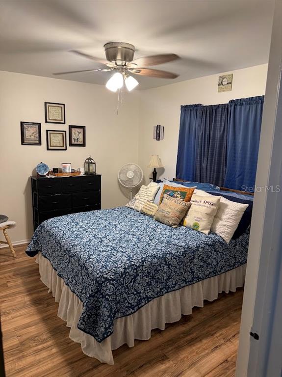 A bedroom features a bed with a blue patterned quilt, a black dresser, and wood flooring — 2514 ABBEY AVENUE, ORLANDO, FL
